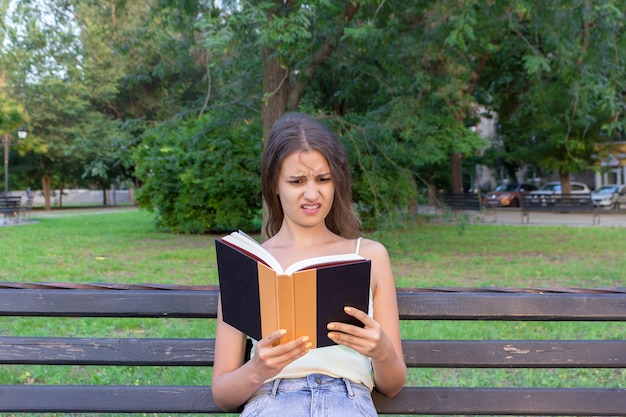 Geschokte en verbaasde vrouw houdt een boek vast en heeft een ontevreden blik