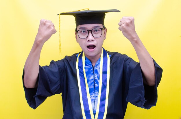 geschokte en verraste aziatische jongeman schreeuwt vrolijk om zijn afstuderen te vieren