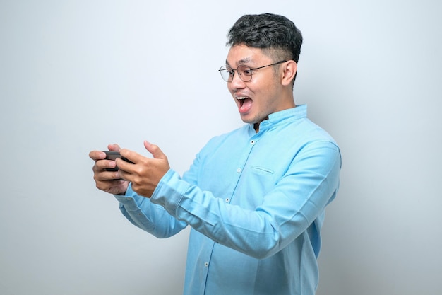 Geschokte jonge knappe Aziatische man die smartphone gebruikt om online goed nieuws te lezen