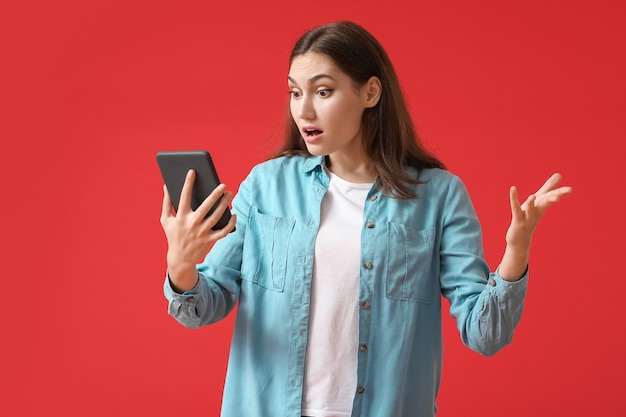 Geschokte jonge vrouw met e-reader op kleur