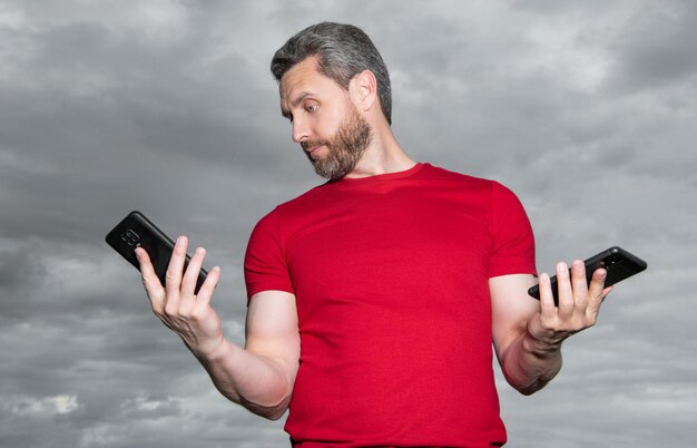 Geschokte man blogger type telefoonbericht draag rode t-shirt