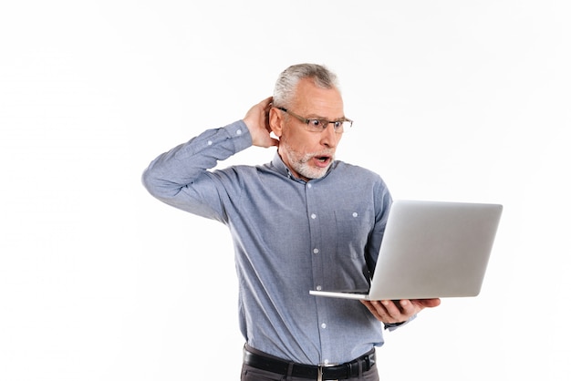 Geschokte mens in oogglazen die laptop geïsoleerde computer met behulp van