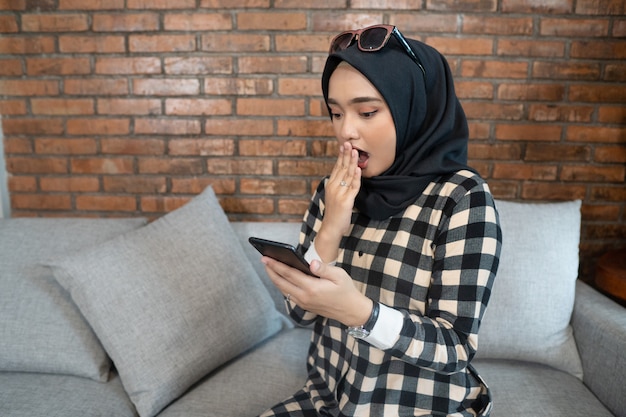 Geschokte moslimvrouw die haar telefoon bekijkt