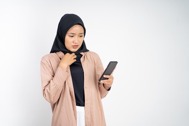 Geschokte moslimvrouw in hijab die een mobiele telefoon gebruikt