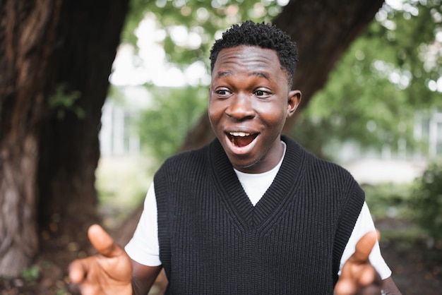 Geschokte verraste jonge Afrikaanse man in het park glimlachend herfst- of lenteseizoen