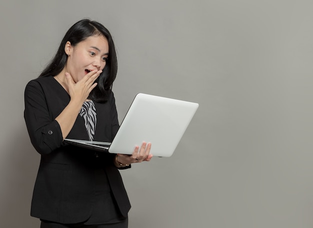 Geschokte zakenvrouw die laptopscherm vasthoudt en bekijkt