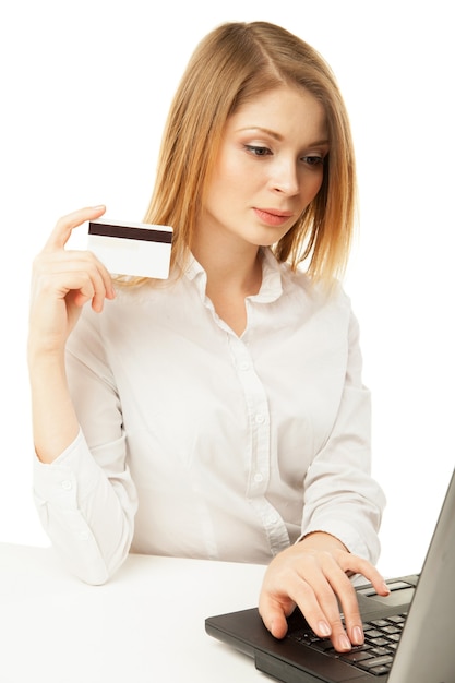 Geschokte zakenvrouw met laptop en creditcard op witte achtergrond