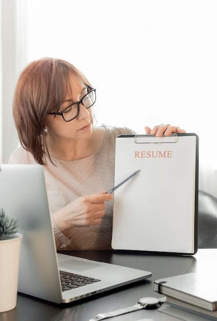 Geschoolde vrouw van middelbare leeftijd online communiceren, studeren op afstand of werken in een wervingsbureau.