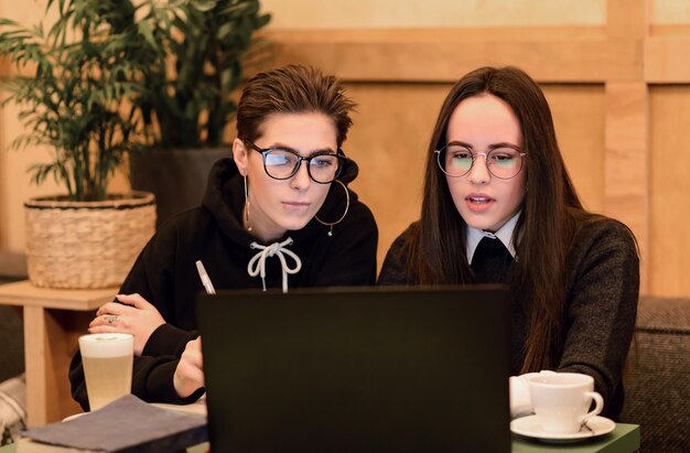 Geschoolde vrouwelijke studenten die onderzoek doen op laptopcomputer die huiswerk maken in de cafetaria