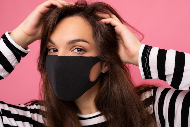 Geschoten portret van jonge brunette aantrekkelijke vrouw die een mediaal gezichtsmasker draagt dat over achtergrond wordt geïsoleerd