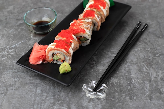 Geselecteerde Focus Salmon Blaze Sushi Roll, Crab Stick, Komkommer en Geroosterde Zalm Gegarneerd met Tobiko. Geserveerd op witte rechthoekige plaat. Ruimte voor tekst kopiëren