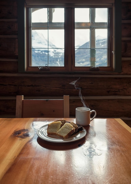 Geserveerd sneetje brood met hete espresso in een kopje op houten lodge in nationaal park