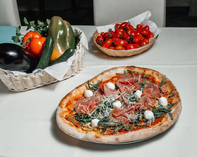 Geserveerde tafel in een pizzeria-restaurant met pizzatomaten en een mand met verse groenten