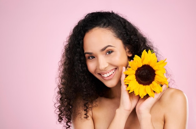 Gesichtsverzorging en schoonheid van vrouw met zonnebloem in studio geïsoleerd op een roze achtergrond mockup Portret glimlach en natuurlijk model met bloem bloem cosmetica of organische behandeling voor gezonde huid