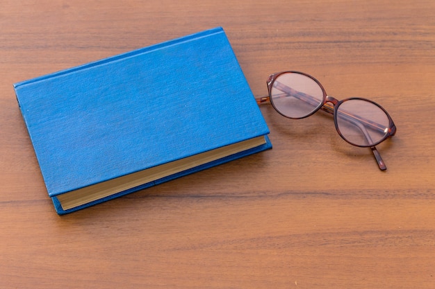 Gesloten boek en bril op houten achtergrond