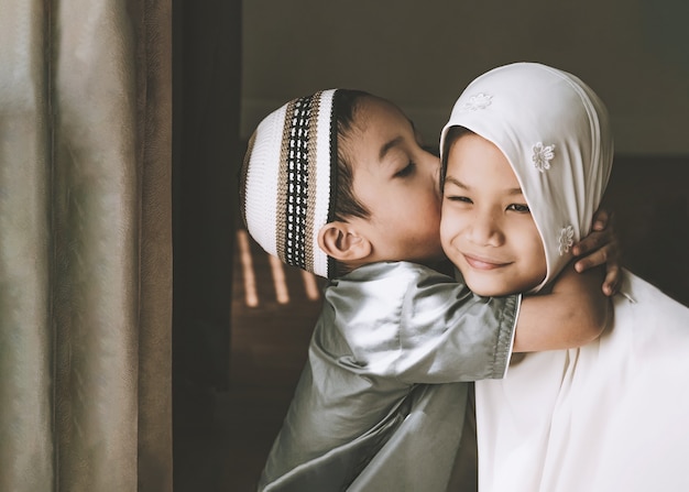 Gesloten schot van Aziatische moslimkinderen, een jonge zus en broer, broer of zus in traditionele islamitische kleding