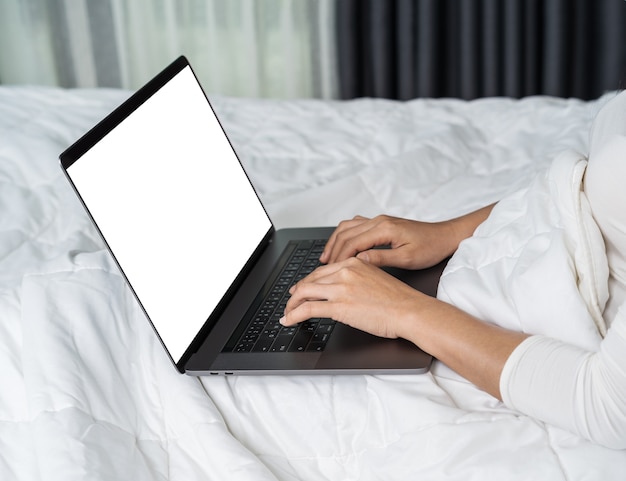 Gesloten vrouw die laptop computer op bed met behulp van