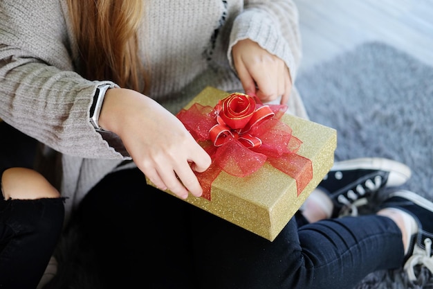 Gesloten vrouwelijke handen binden de geschenkdoos van het lint samen in kerst- en verjaardagsfeestje