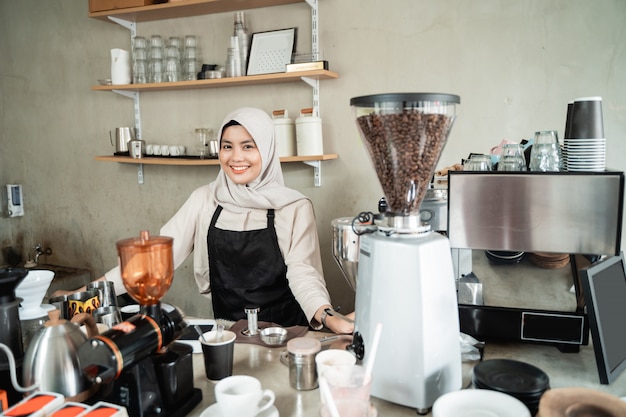 Gesluierde barista lachend bij het houden van een kopje koffie