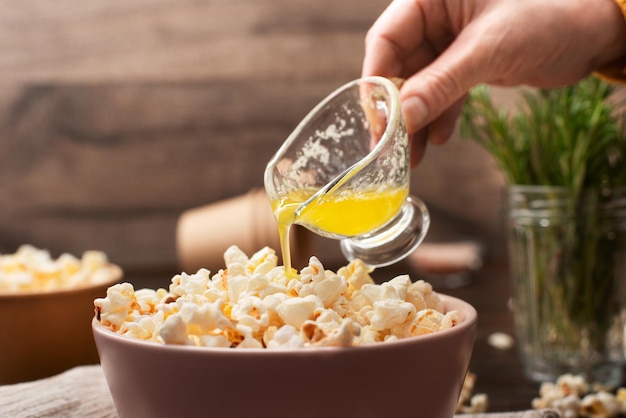 Gesmolten boter wordt gegoten op popcorn in kleikom op keukentafel