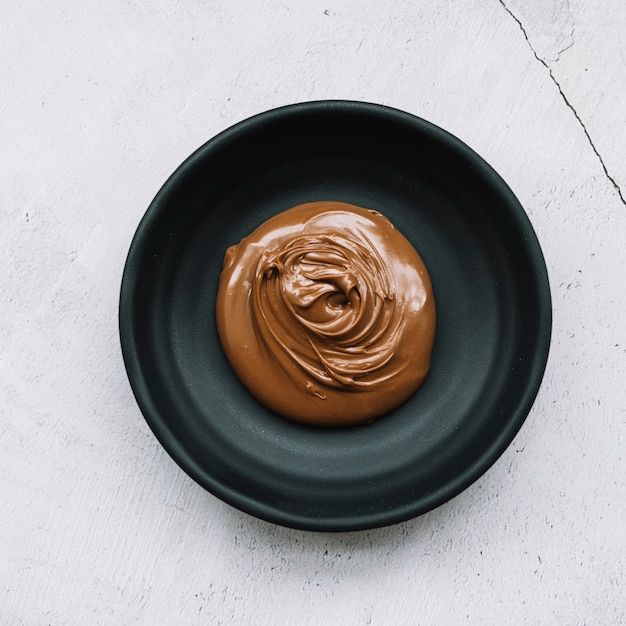 Foto gesmolten chocolade in zwarte kom over de witte achtergrond