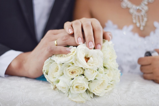 Gesneden afbeelding van bruid en bruidegom die een roosbouquet aanraken