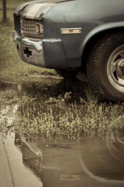 Foto gesneden afbeelding van een auto bij een plas op het veld