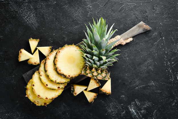 Gesneden ananas op een zwarte achtergrond Tropisch fruit Bovenaanzicht Gratis exemplaarruimte