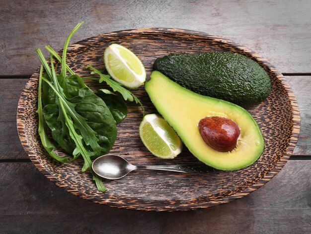 Gesneden avocado met limoenspinazie en rucola op houten plaat