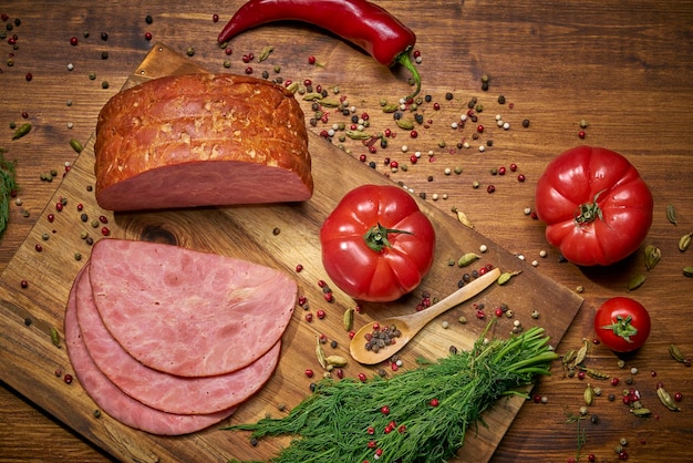 Gesneden bacon met tomaten, rode peper en groen kruid op een houten ondergrond