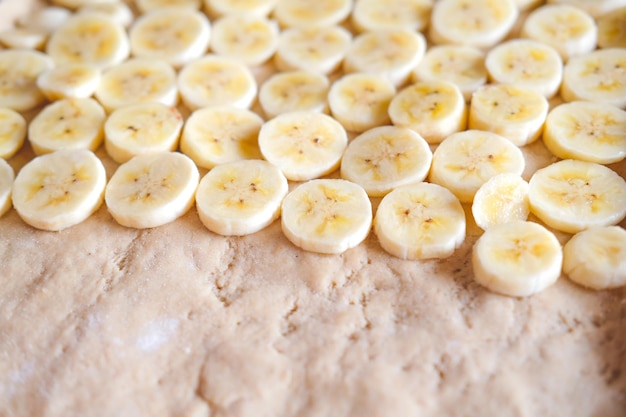 Foto gesneden banaan op deeg bij het maken van bananenpizza close-up