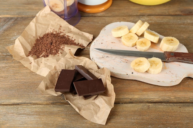 Gesneden banaan op snijplank en gehakte chocolade op houten achtergrond