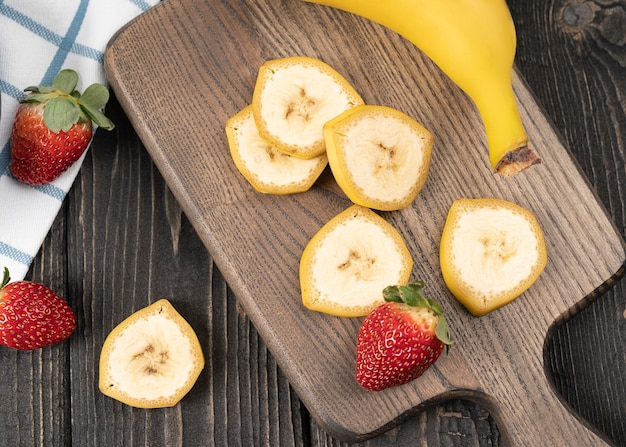 Gesneden bananen met aardbeien op een houten bureau close-up