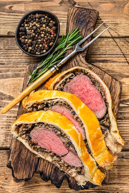 Gesneden beef wellington-gebak op een houten snijplank.