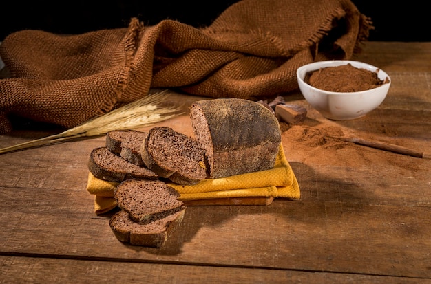 Gesneden brood gemaakt met cacau en chocolade op gele doek op rustieke houten tafel met ingrediënten.