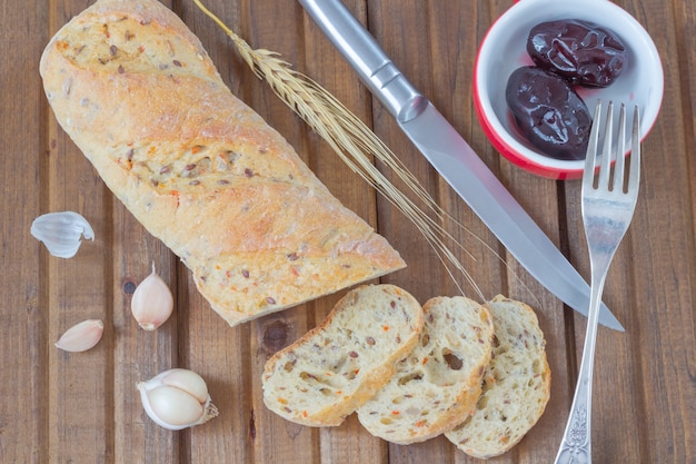 Gesneden brood, gepekelde pruimen op het bord, peper, mes en vork