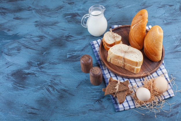 Gesneden brood, kruik melk en ei op een theedoek, op de blauwe tafel.