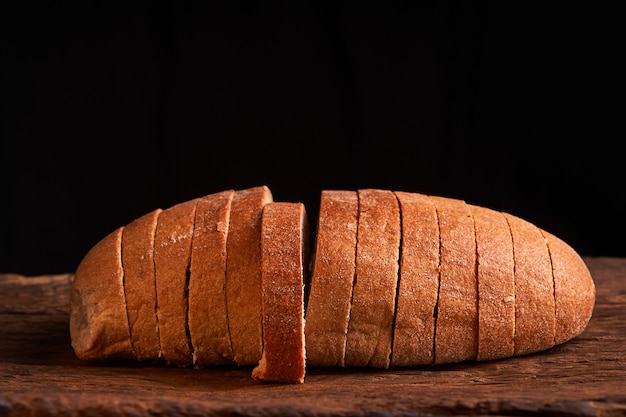 Gesneden brood op een houten lijst en op een zwarte achtergrond