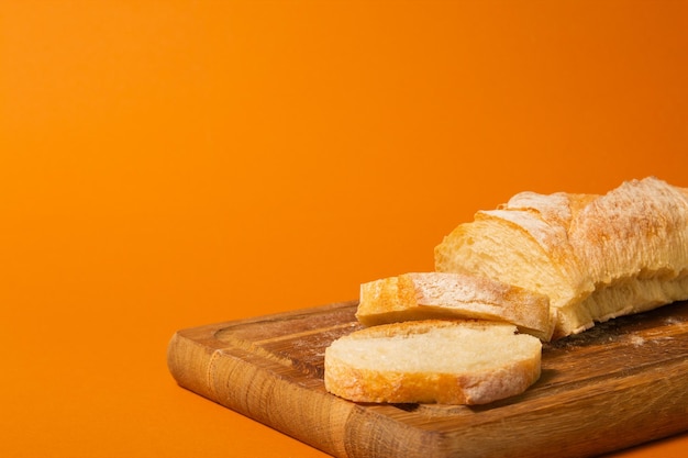 Gesneden brood stokbrood op een houten snijplank op een terracote kleur achtergrond Closeup