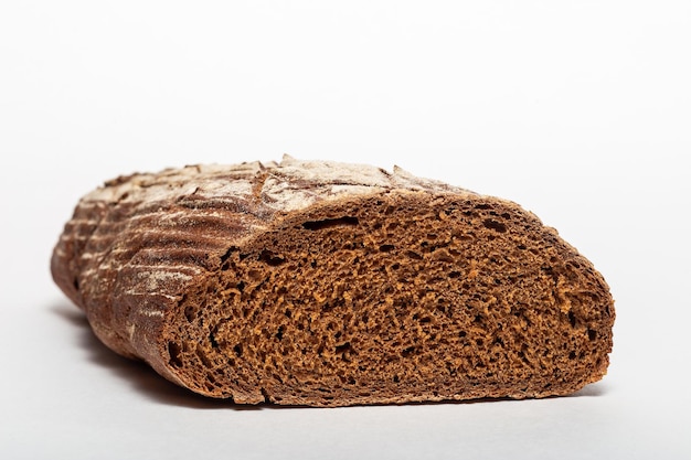 Gesneden brood van zwart roggebrood met sneden van een mes erop en bestrooid met witte bloem geïsoleerd op een witte achtergrond Gezond eten concept Closeup zijaanzicht van brood