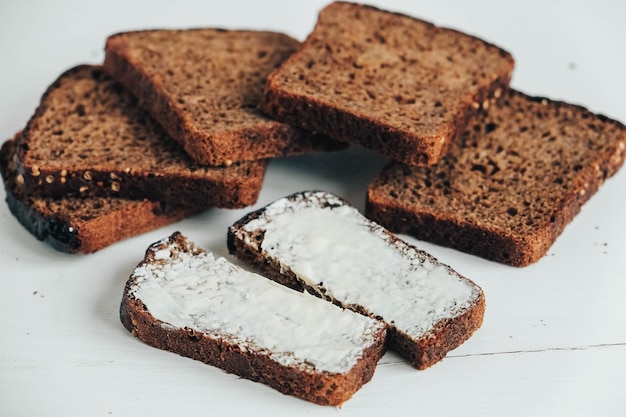 Gesneden bruin brood met boter op een witte houten achtergrond. Bovenaanzicht. Kopiëren, lege ruimte voor tekst