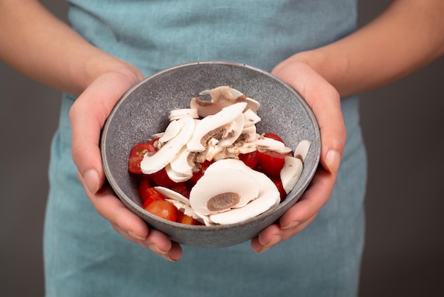 Gesneden champignons en tomatenstukjes in een slakom bereiden gezond voedsel met groenten