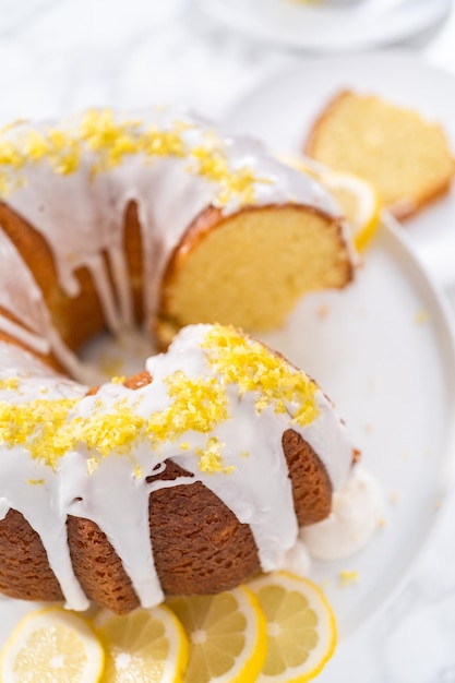 Gesneden citroen bundt cake versierd met citroenschil op een taartplateau.