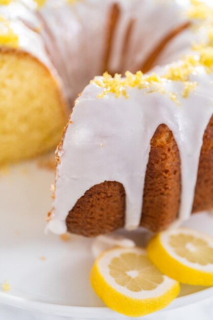 Gesneden citroen bundt cake versierd met citroenschil op een taartplateau.