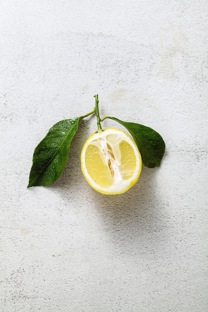 Gesneden citroen op een witte stenen tafel met bladeren.