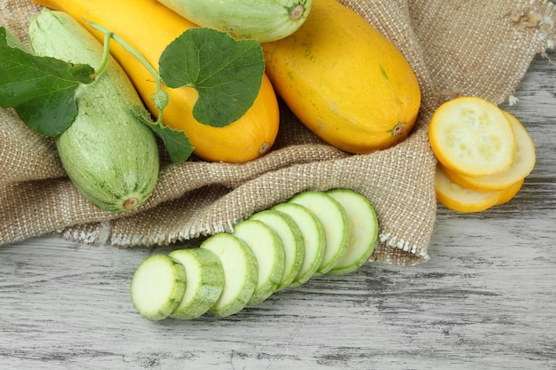 Gesneden en hele rauwe courgette op houten tafel