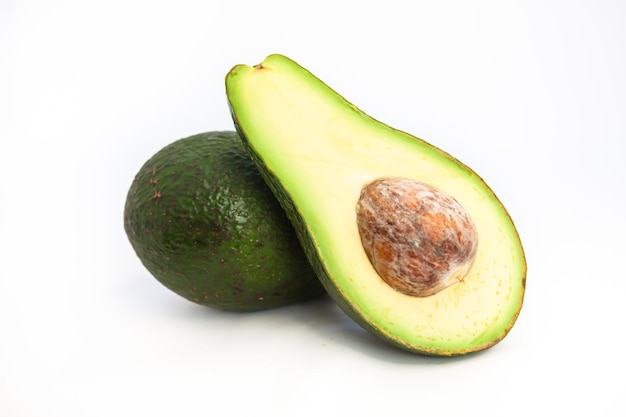 Gesneden en hele rijpe avocado's op witte achtergrond