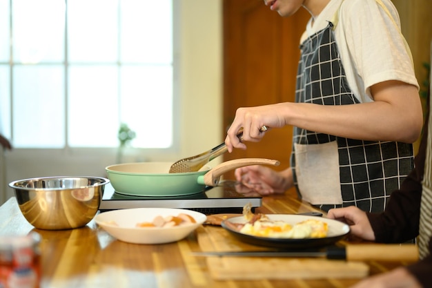Gesneden foto van een homoseksueel stel dat samen een heerlijke maaltijd bereidt in een moderne keuken