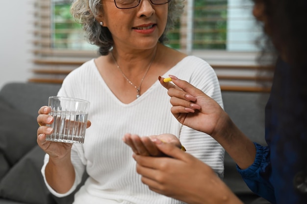 Gesneden foto van een vrouwelijke verzorger die de dosering van medicijnen aan een oudere vrouw uitlegt.