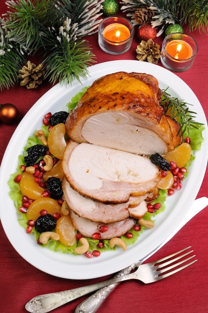 Gesneden gebakken kalkoenham met fruitgarnituur op de kersttafel